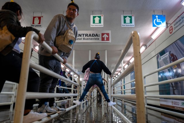 Commuters climb railings to avoid the water in the flooded entrance of Buenavista metro station during heavy rain in Mexico City, Saturday, August 17, 2024. (Photo by Jon Orbach/AP Photo)
