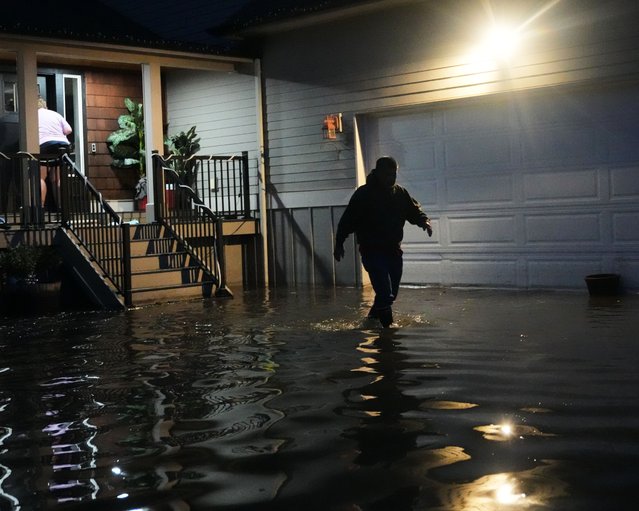 Haji Higa, right, and Lydia Heglin, left, walk through floodwaters at their front door after heavy rains led to historic flooding in the region Saturday, December 13, 2025, in Burlington, Wash. (Photo by Lindsey Wasson/AP Photo)