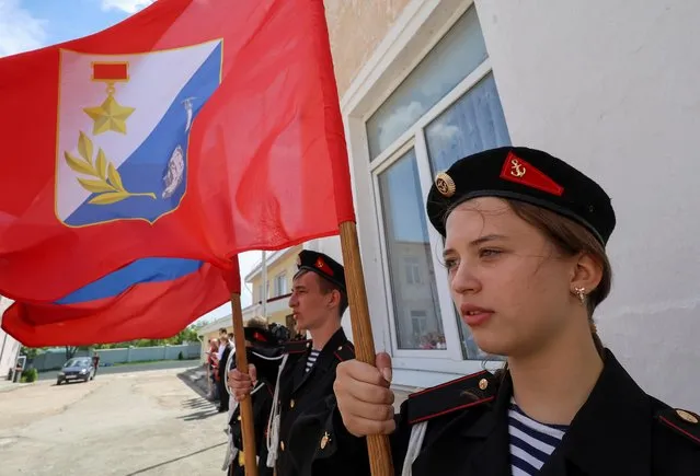 Participants hold flags during a demonstration lesson that is part of an extracurricular military-patriotic program, which involves weapon training, first aid treatment, camping skills and other courses, in Sevastopol, Crimea on May 19, 2023. (Photo by Alexey Pavlishak/Reuters)