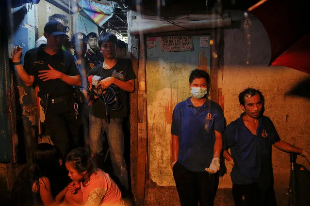 Funeral parlour workers, policemen, reporters and the relatives of five people who were killed, wait for investigation to be done outside a house in Manila, Philippines early November 1, 2016. According to police and witnesses, unknown masked gunmen killed five people inside a house that is a known drug den. (Photo by Damir Sagolj/Reuters)