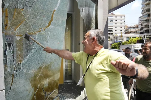 A protester smashes windows at Byblos Bank during a protest demanding the release of depositors' trapped savings, in Beirut, Lebanon, Thursday, June 15, 2023. Since Lebanon fell into a financial crisis in 2019, the banks have imposed informal capital controls, restricting depositors from accessing their funds, while the country's currency has collapsed and inflation has spiraled. (Photo by Hussein Malla/AP Photo)