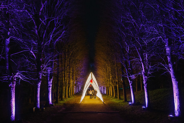 Visitors walk through a light tunnel during the “Lumieres-en-Seine” holiday lights show, at the National Estate of Saint-Cloud in Saint-Cloud, near Paris on December 12, 2024. (Photo by Dimitar Dilkoff/AFP Photo)