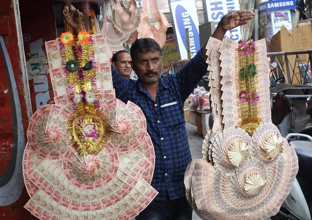 A man sells garlands made of Indian currency notes at a market in Jammu, India, November 13, 2016. (Photo by Mukesh Gupta/Reuters)