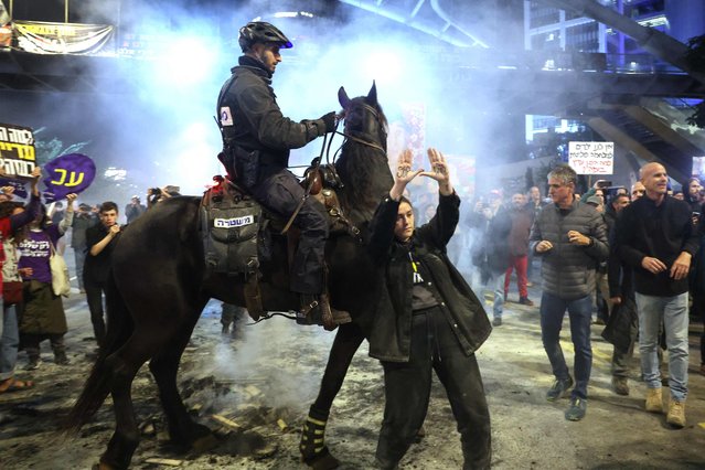 A protester gestures as Israeli mounted police disperse the crowds during a demonstration calling for the release of hostages held captive in Gaza by Palestinian militants since the October 7 attacks, outside the Defence Ministry headquarters in Tel Aviv on January 4, 2025 amid the ongoing war in the Palestinian territory between Israel and Hamas. (Photo by Jack Guez/AFP Photo)
