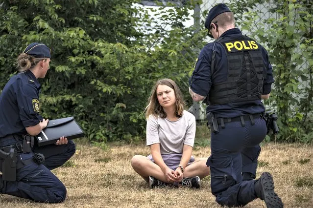 Police officers talk to the Swedish climate activist Greta Thunberg as they move activists from the organization “Ta Tillbaka Framtiden” (Take back the future) who are blocking the entrance to the Oljehamnen neighbourhood in Malmo, Sweden, Monday, June 19, 2023. Local newspaper Sydsvenskan reported Wednesday, July 5, 2023, that Swedish prosecutors have charged Thunberg with disobedience to law enforcement in connection with a protest in Malmö last month. (Photo by Johan Nilsson/TT News Agency via AP Photo)