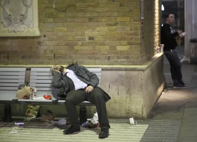 A man rests at Liverpool Street station during the Christmas party season, December 18, 2015. (Photo by Paul Hackett/Reuters)