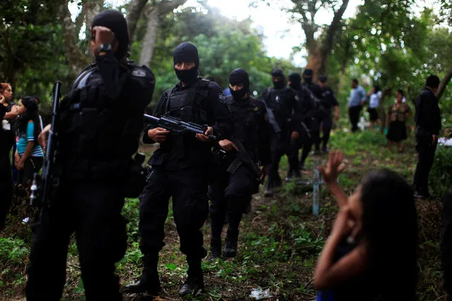 A girl waves at Salvadoran police officers participating in the funeral ceremony for their colleague Lorenzo Rojas Herrera and his son Marvin in Quezaltepeque, El Salvador, November 18, 2016. Sergeant Lorenzo Rojas and his son were killed by suspected members of the Mara Salvatrucha gang, according to the police. (Photo by Jose Cabezas/Reuters)