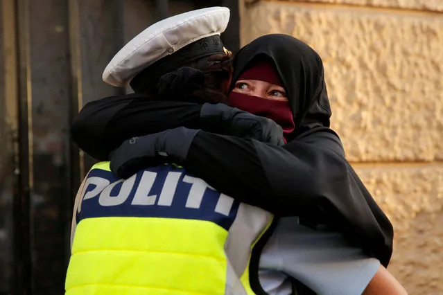 Ayah, 37, a wearer of the niqab weeps as she is embraced by a police officer during a demonstration against the Danish face veil ban in Copenhagen, Denmark, August 1, 2018. (Photo by Andrew Kelly/Reuters)
