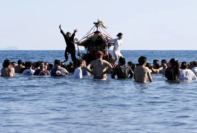 A woman jumps from a “mikoshi” or portable shrine as people carry it into the sea during a festival to wish for calm waters in the ocean and good fortune in the new year in Oiso, Kanagawa prefecture, west of Tokyo, Japan, January 1, 2016. (Photo by Yuya Shino/Reuters)