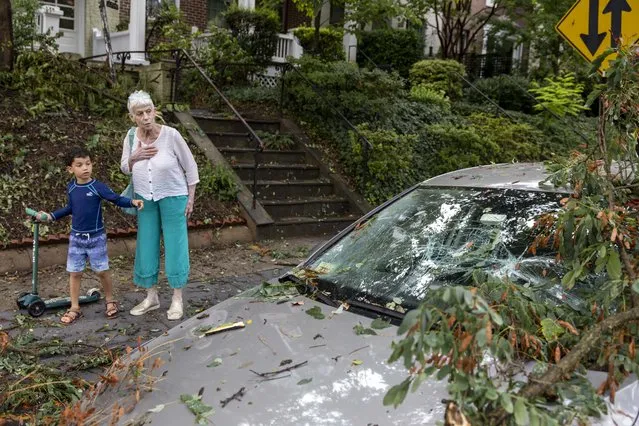 Holly Blum and her grandson Julien Blum, 5, look at a damaged car following a brief storm in Washington, D.C. on July 29, 2023. (Amanda Andrade-Rhoades/For The Washington Post)