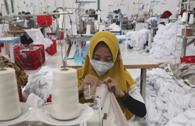 Workers wearing face masks to curb the spread of the coronavirus outbreak operate sewing machines at a factory that makes Muslim women's prayer robes in Depok, Indonesia, Wednesday, April 7, 2021. (Photo by Tatan Syuflana/AP Photo)