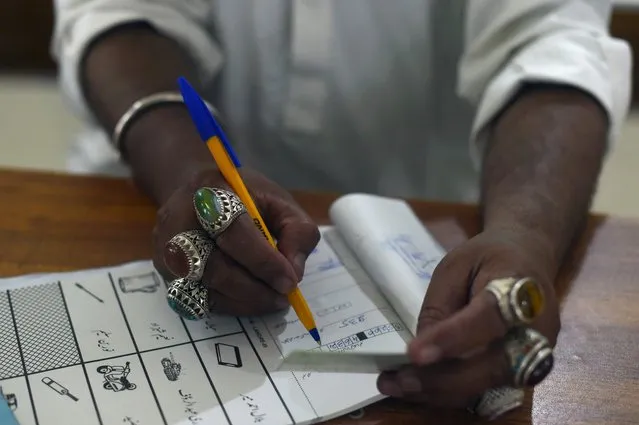 A election official man notes down information of an ID of a voter during Pakistan's general election at a polling station in Lahore on July 25, 2018. Pakistanis voted July 25 in elections that could propel former World Cup cricketer Imran Khan to power, as security fears intensified with a voting-day blast that killed at least 28 after a campaign marred by claims of military interference. (Photo by Wakil Kohsar/AFP Photo)