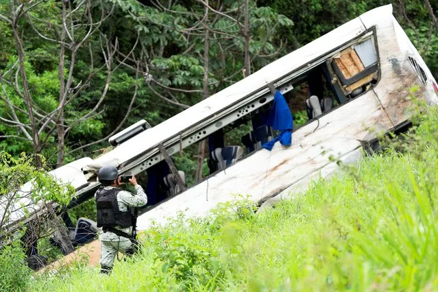 A member of the National Guard takes pictures of a passenger bus that plunged off a highway killing several people, in Tepic, Mexico on August 3,2023. (Photo by Christian Ruano/Reuters)