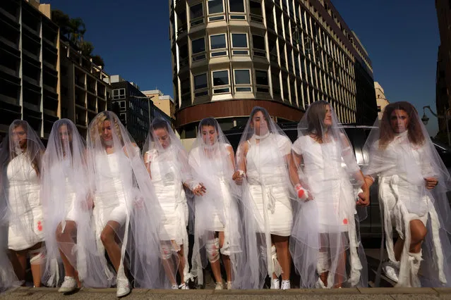 Activists from the Lebanese NGO Abaad (Dimensions), a resource centre for gender equality, dressed as brides and wearing injury patches hold a protest in downtown Beirut on December 6, 2016, against article 522 in the Lebanese penal code. The article shields rapists from prosecution on the condition that they marry their victim, a phenomenon that is still practised in the country, especially among conservative families whose chief aim is to preserve the family' s so- called “honour”. (Photo by Patrick Baz/AFP Photo)