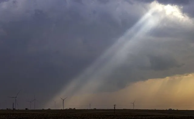Sunlight filters through storm clouds onto a wind turbine as severe weather rolls through the midwest on Tuesday, April 4, 2023, south of Stuart, Iowa. Strong storms, likely including tornadoes, are expected to hit parts of the Midwest and South beginning Tuesday evening. (Photo by Chris Machian/Omaha World-Herald via AP Photo)