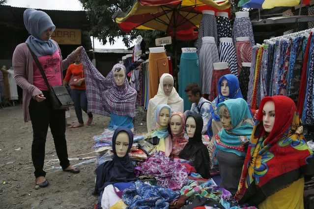 A customer holds a hijab at a stall, at the Tanah Abang textile market in Jakarta, Indonesia January 13, 2016. Indonesia's central bank is expected to cut its key policy rate on Thursday to boost growth after saying since October that it sees room to loosen monetary policy. (Photo by Reuters/Beawiharta)
