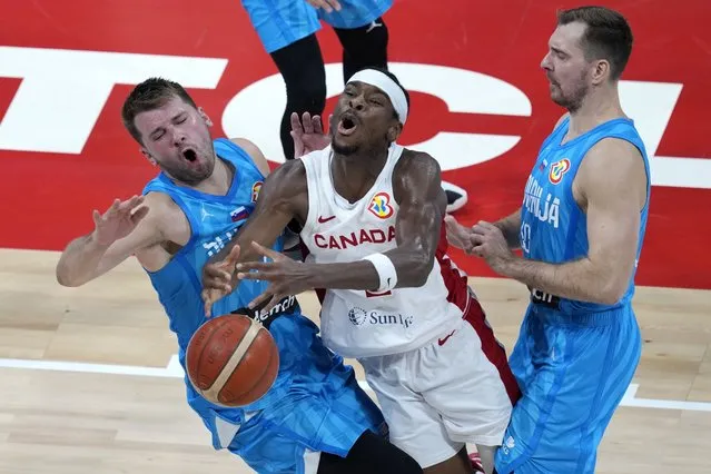 Canada's Shai Gilgeous-Alexander, center, collides with Slovenia's Luka Doncic, left, as Slovenia's Zoran Dragic defends during the second half of a Basketball World Cup quarterfinal game in Manila, Philippines, Wednesday, September 6, 2023. (Photo by Aaron Favila/AP Photo)