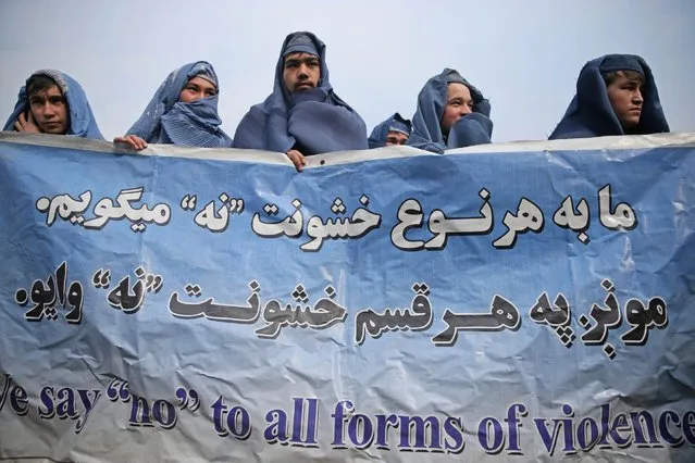 Male civil society members wear burqas to protest violence against women, ahead of International Women's Day, in Kabul, Afghanistan, Thursday, March 5, 2015. The banner reads, "we say no to all forms of violence." (AP Photo/Massoud Hossaini)