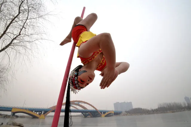 A woman wearing traditional opera make-up performs pole dance by the side of a lake under sub-zero temperatures, in Handan, Hebei province, China, January 20, 2016. Picture taken on January 20, 2016. (Photo by Reuters/China Daily)