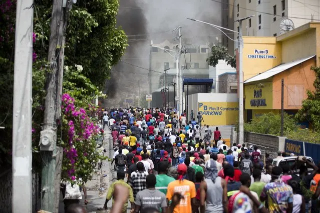 People walk in the street during protests over the fuel price increase in Port-au-Prince, Haiti, on Saturday, July 7, 2018. On Friday, the government announced that it would raise the prices of gasoline, diesel and kerosene from 38 percent to 51 percent beginning Saturday. (Photo by Dieu Nalio Chery/AP Photo)