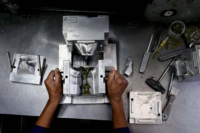 Wax machine operator Ronald Moore opens a wax form during the production of a “Spirit of Ecstasy”. (Photo by Stefan Wermuth/Reuters)