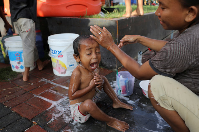 A child reacts while taking a shower at a camp for displaced earthquake and liquefaction victims in Palu, Central Sulawesi, Indonesia, October 12, 2018. (Photo by Jorge Silva/Reuters)