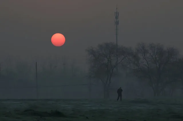 A man walks during sunrise in smog on a polluted day as a red alert issued for air pollution in Beijing, China, December 19, 2016. (Photo by Jason Lee/Reuters)