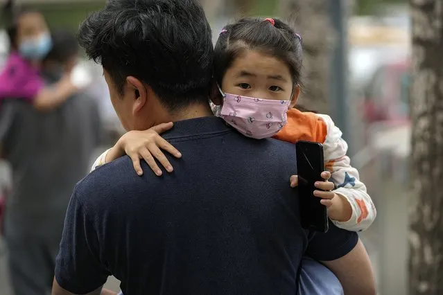 People carry their child wearing face masks to help curb the spread of the coronavirus head to a kindergarten in Beijing, Wednesday, June 9, 2021. (Photo by Andy Wong/AP Photo)