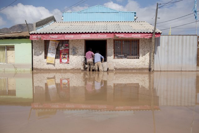 Two men stand in a flooded street at a shop in Copiapo, Chile, Thursday, March 26, 2015. (Photo by Pablo Sanhueza/AP Photo)