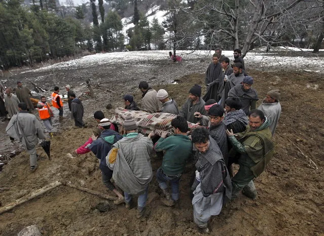 Villagers carry the body of a victim at the site of a damaged house after a hillside collapsed onto a house at Laden village, west of Srinagar, March 30, 2015. (Photo by Danish Ismail/Reuters)