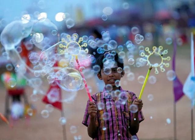 A boy blows bubbles to show customers at a stall near a beach in Colombo, Sri Lanka December 8, 2016. (Photo by Dinuka Liyanawatte/Reuters)