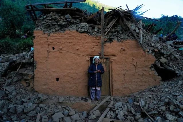 A woman stands in front of earthquake damaged house in Jajarkot district, northwestern Nepal, Sunday, November 5, 2023. (Photo by Niranjan Shrestha/AP Photo)