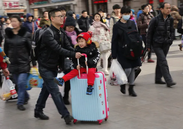 A man carries a child on a suitcase as they head to the Beijing Railway Station during the travel rush ahead of the upcoming Spring Festival in Beijing, China, February 5, 2016. (Photo by Kim Kyung-Hoon/Reuters)
