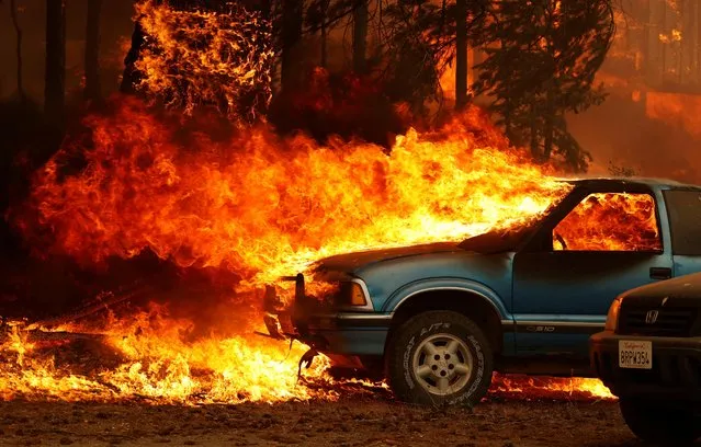 Wind-driven flames shoot horizontally out of the windshield of a car on fire at the Dixie Fire, a wildfire near the town of Greenville, California, U.S. August 5, 2021. (Photo by Fred Greaves/Reuters)