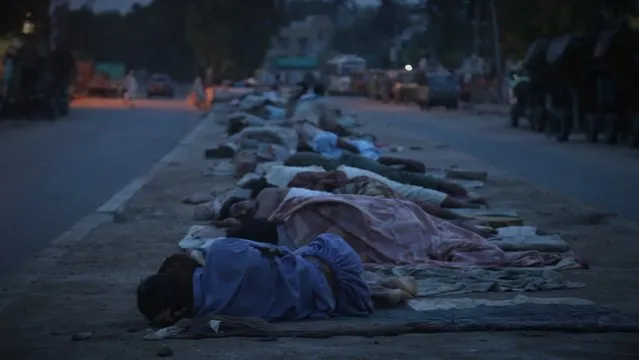 Homeless people sleep on a roadside during micro smart lockdown after new cases of COVID-19 were reported in Karachi, Pakistan, 27 July 2021. Countries around the world are taking increased measures to stem the widespread of the COVID-19 disease. (Photo by Rehan Khan/EPA/EFE)