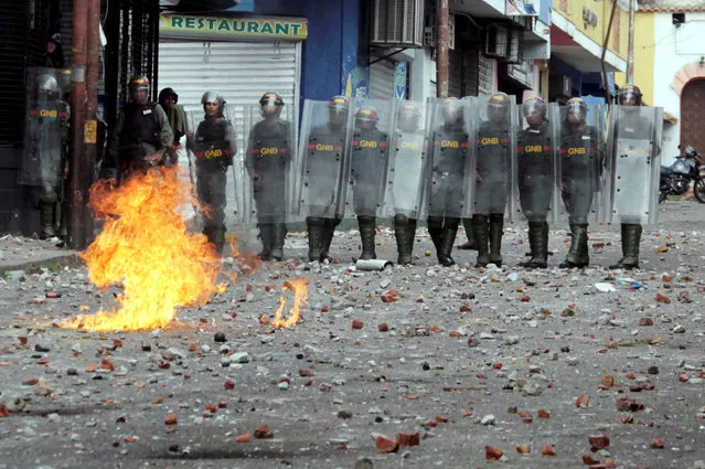 Security forces look on while clashing with opposition supporters participating in a rally against Venezuelan President Nicolas Maduro's government and to commemorate the 61st anniversary of the end of the dictatorship of Marcos Perez Jimenez in Tachira, Venezuela January 23, 2019. (Photo by Carlos Eduardo Ramirez/Reuters)