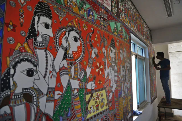 In this November 30, 2018 photo, an Indian artist paints a wall with traditional Mithila art at the newly built Janakpur train station in Nepal from where a new 34 kilometers (21 miles) long rail line runs to Jay Nagar in the Indian state of Bihar. (Photo by Niranjan Shrestha/AP Photo)