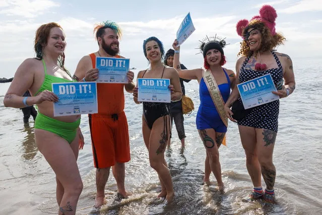 People pose for a photo with certificates after swimming in the ocean for the 121st annual Coney Island Polar Bear Club's New Year's Day plunge at Coney Island beach in the Brooklyn borough of New York, New York, USA, 01 January 2024. (Photo by Sarah Yenesel/EPA)