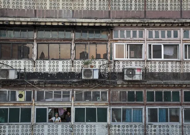 Residents look out of a window of an apartment in south Mumbai March 15, 2015. The cost for buying a 500 square feet (55 square meters) one-bedroom apartment in this building is around 17,000 Indian rupees per square feet ($ 270) or 8,500,000 Indian rupees ( $136,000). The rent for an apartment in the same building is around 12,000 Indian rupees ($ 190) per month. (Photo by Danish Siddiqui/Reuters)