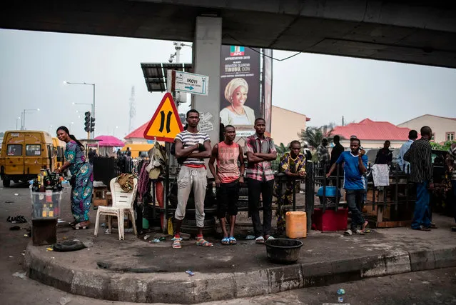 People stand at a crossroad under a bridge in Lagos on February 16, 2019 after Nigeria's electoral watchdog postponed presidential and parliamentary elections for one week, just hours before polls were due to open. The two main political parties swiftly condemned the move and accused each other of orchestrating the delay as a way of manipulating the vote. (Photo by Stefan Heunis/AFP Photo)