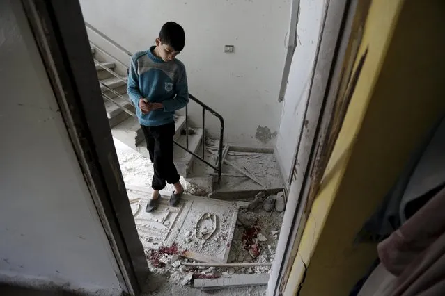 A boy inspects the damage as blood stains are seen on the ground at a site hit by shelling in the rebel-controlled area of Khan Sheikhoun, in Idlib province, Syria March 4, 2016. (Photo by Khalil Ashawi/Reuters)