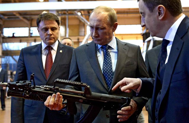 Russia's President Vladimir Putin (C) holds an ADS dual-medium amphibious assault rifle, which is equally accurate when fired underwater or on dry land, during a visit to an arms factory in the city ancient Russian city of Tula, some 119 km (120 miles) south of Moscow, on January 20, 2014. (Photo by Alexei Nikolsky/AFP Photo/RIA-Novosti)