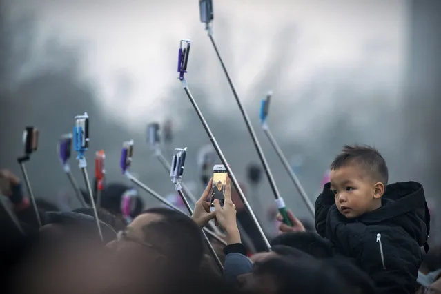 Tourists take photos of the daily flag-raising ceremony in Tiananmen Square on the eve of the opening session of China's National People's Congress (NPC) in Beijing, Tuesday, March 5, 2019. A year since removing any legal barrier to remaining China's leader for life, Xi Jinping appears firmly in charge, despite a slowing economy, an ongoing trade war with the U.S. and rumbles of discontent over his concentration of power. (Photo by Mark Schiefelbein/AP Photo)