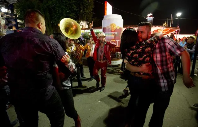 In this April 10, 2015 photo, a man holds his dance partner tight as Juan Ramon Nava from the Mexican Norteño band, El Primo, performs at the Texcoco Fair on the outskirts of Mexico City. Fairgoers pay roving bands of musicians to play songs. (Photo by Eduardo Verdugo/AP Photo)