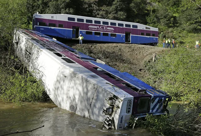 Workers investigate the scene of a derailed Altamont Corridor Express train Tuesday, March 8, 2016, in Sunol, Calif. Spokesman Francisco J. Castillo said investigators believe a mudslide swept a tree onto the tracks, derailing a car on the Altamont Corridor Express train Monday evening. The San Francisco Bay Area has been inundated with thunderstorms in recent days that have swamped roadways and creeks. (Photo by Ben Margot/AP Photo)