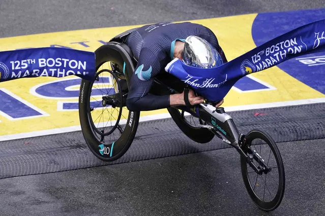 Marcel Hug, of Switzerland, breaks the finish line with his helmet to win the men's wheelchair division at the Boston Marathon in Boston, Monday, October 11, 2021. (Photo by Charles Krupa/AP Photo)