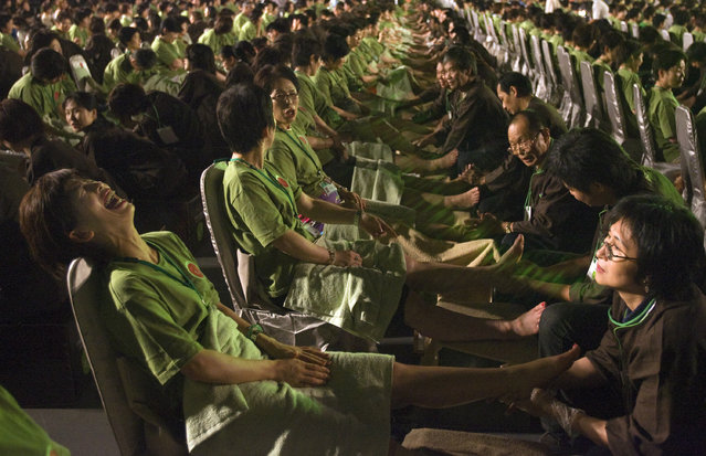 A visitor from Japan reacts to a therapist's touch during a mass foot reflexology session at the Taipei Arena July 1, 2008. The tourism bureau of Taiwan looked to break the Guinness World Record of “Most people receiving reflexology/foot massage simultaneously” with 2000 participants from Japan, South Korea, Hong Kong and Singapore undergoing 20 minutes of reflexology treatment together. (Photo by Nicky Loh/Reuters)