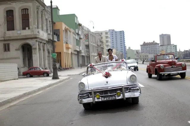 Newlyweds ride in a vintage car on the seaside front El Malecon in Havana, March 17, 2016. (Photo by Ueslei Marcelino/Reuters)