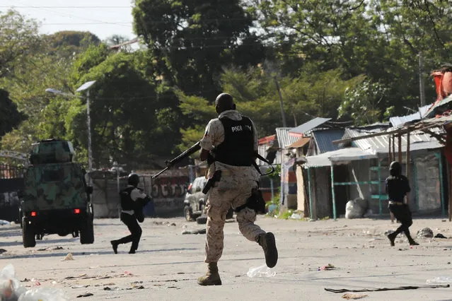 Police officers run holding their guns while confronting a gang during a protest against Prime Minister Ariel Henry's government and insecurity, in Port-au-Prince, Haiti on March 1, 2024. (Photo by Ralph Tedy Erol/Reuters)