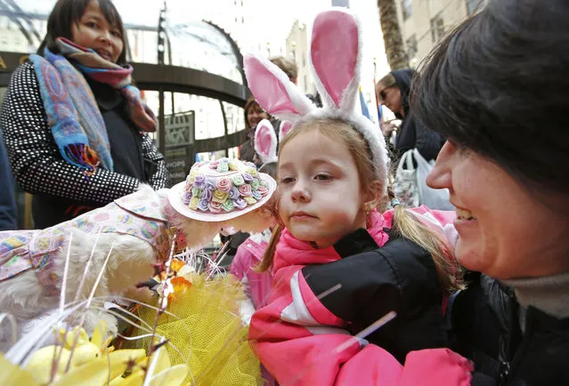 Dace Anderson, right, of Latvia, holds her daughter Ava, 4, close to a dog named Coco Chanel for a kiss that hopefully will stem Ava's tears during the annual Easter parade near St. Patrick's Cathedral, Sunday, March 27, 2016, in New York. (Photo by Kathy Willens/AP Photo)